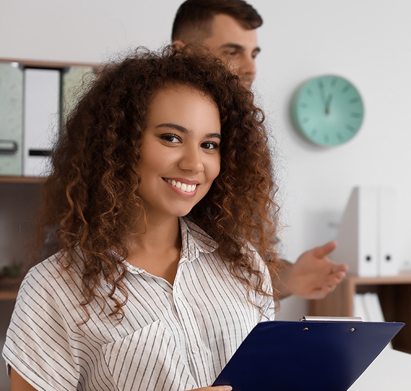 A health unit coordinator sits at a hospital workstation, answering phone calls and updating patient information to support communication and coordination among medical staff.